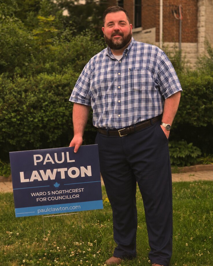 Paul Lawton standing beside a Paul Lawton for Northcrest lawn sign